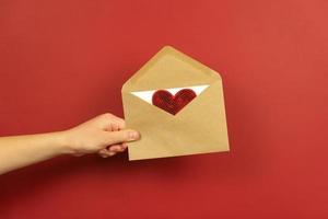 A boy holds an envelope with a love letter and red heart in it photo