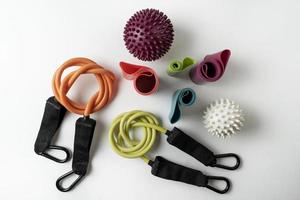 diferentes equipos coloridos para ejercicios de fitness y deportivos mancuernas y expansores naranjas, pelotas de fitness y bandas sobre un fondo blanco foto