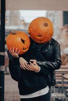 un chico y una chica con cabezas de calabaza posando en la calle foto