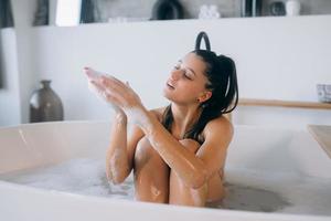 mujer joven disfruta de la espuma mientras toma un baño foto