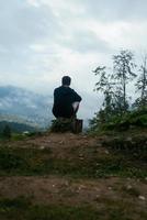 chico en la cima de una colina disfrutando de la vista de la naturaleza foto