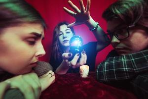 Group of people and woman fortune teller with crystal ball photo