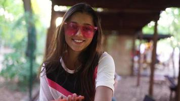 mujer joven con gafas de sol rosas sonríe a la cámara video