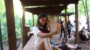 giovane donna nel rosa occhiali da sole prende autoscatto e pose con inteligente Telefono video