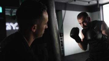 hombre en gimnasio de boxeo golpea saco de boxeo video