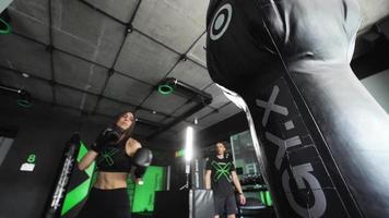 Woman in a boxing gym kicks punching bag video