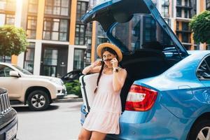 Woman packing her suitcase into luggage boot of the car. photo