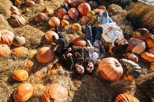 Young girls lie on haystacks among pumpkins. View from above photo