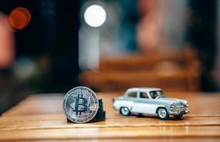 Silver bitcoin and Moskvich 401 on the table, glowing background photo