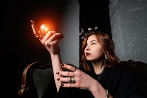 Woman in black suit holding crystal ball photo