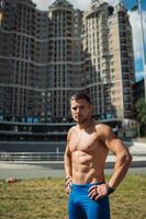 Muscular guy with a naked torso on the background of a tall building photo