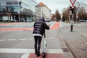 Beautiful young woman riding an electric scooter, street-style photo