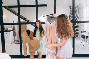 Two women choose and try on clothes at home photo