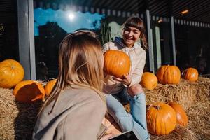 Girls have fun among pumpkins and haystacks on a city street photo