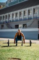 joven sube el listón en el estadio, entrenamiento al aire libre foto