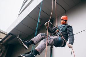 Industrial climber in uniform and helmet rises photo