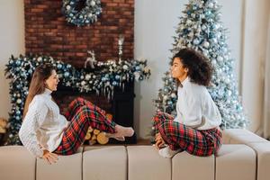 Two female student friends sitting on the couch at home. photo