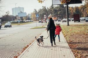 Happy mother and her daughter walk with dog at the street. photo