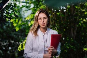 Young agricultural engineer working in greenhouse. Young female scientist looking at the camera photo