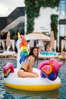 Woman on inflatable unicorn toy mattress float in pool. photo