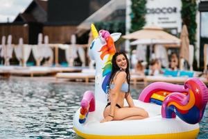 Woman on inflatable unicorn toy mattress float in pool. photo