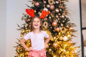 Portrait of little girl wearing deer christmas hat. Winter holidays and people concept. photo