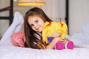 niña con un juguete en la cama foto