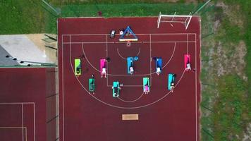 Group of young people doing workout on the red sportground. Top aerial view. photo
