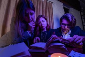 Two women and a guy are reading a mysterious books, close view photo