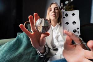 Woman in business suit holding crystal ball and six spade photo