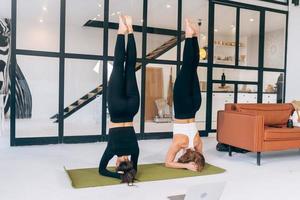 Two young woman working out indoors, doing yoga exercise on mat photo