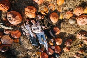 Young girls lie on haystacks among pumpkins. View from above photo