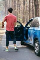 Handsome man standing on the road near opened door of his car. photo