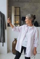 Cheerful confident excited dreamy elderly female taking selfie photo