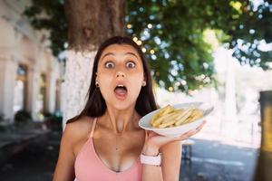 Young women hold french fries on white plates. Street cafe photo