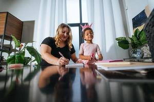 madre e hija dibujan creativamente en la mesa foto