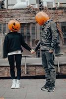 A guy and a girl with a pumpkin heads. Couple holding hands photo