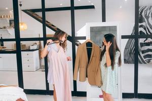 Two women choose and try on clothes at home photo