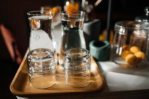 cuatro vasos de vidrio en el mostrador del bar con accesorios para servir. foto