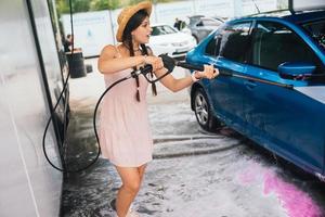 Brunette from a high-pressure hose washes the car photo