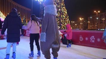 People enjoy ice skating in the street around Christmas tree in rink. photo