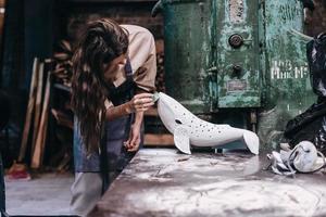 Portrait of young woman carefully work on a ceramic whale in workshop. photo