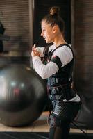 EMS training. Girl doing exercises in a suit with cables. photo