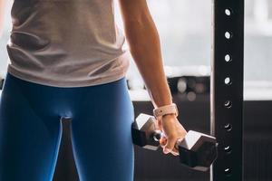 Slender athletic girl performs physical exercises with dumbbells. photo