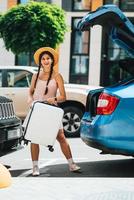 Woman packing her suitcase into luggage boot of the car. photo