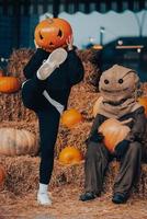 Young woman with a pumpkin on her head posing with a scarecrow photo