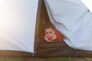 Young woman peeking out of the tent with only her head sticking out photo