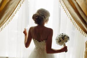 beautiful bride in a wedding dress, by window. photo