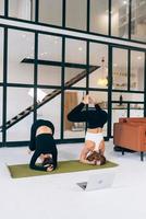 Two young woman working out indoors, doing yoga exercise on mat photo