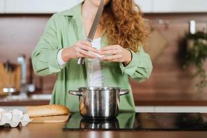 mujer joven está preparando comida en la cocina. batiendo huevos. foto